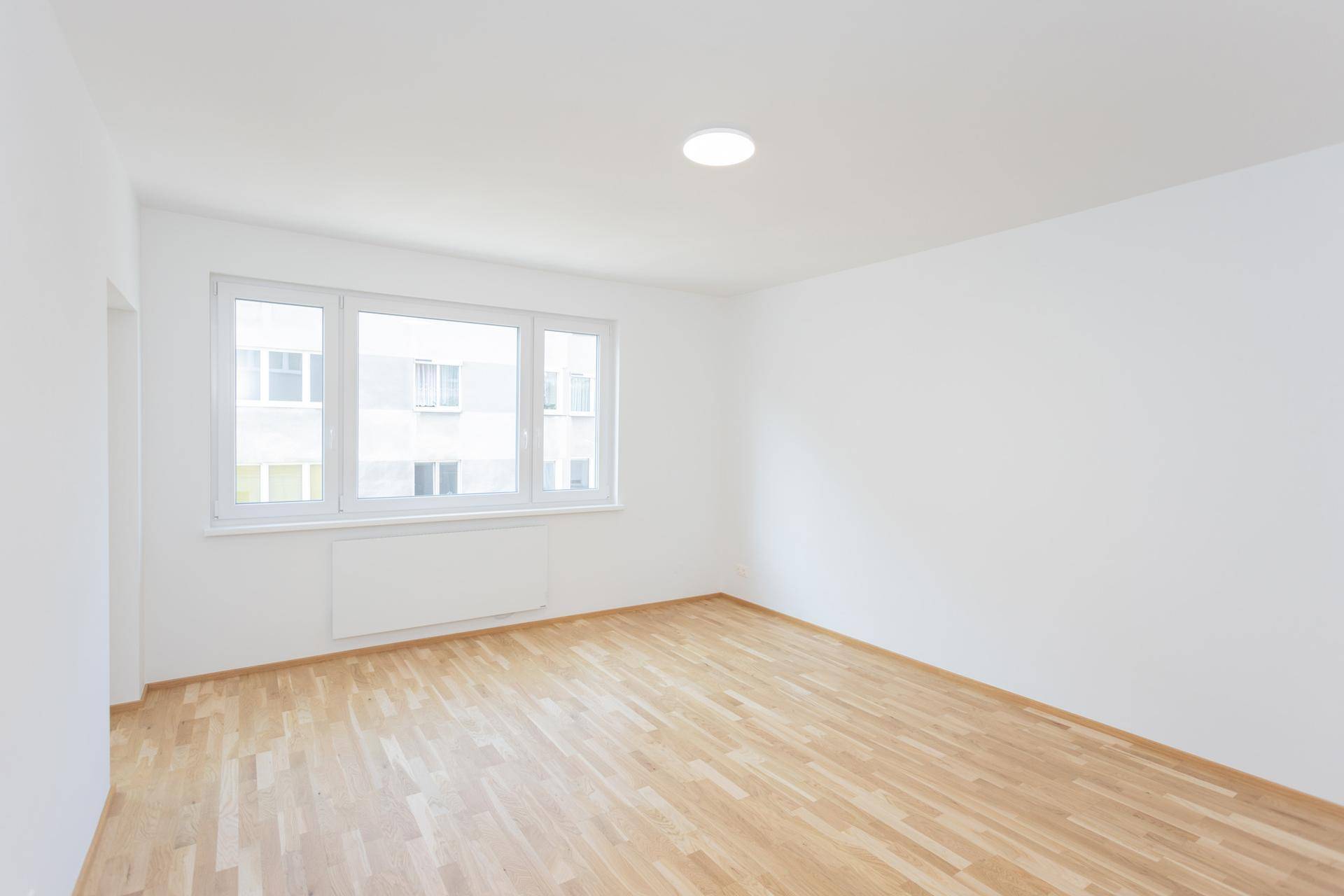 Geräumiger Wohnbereich mit hellem Parkettboden und großen Fenstern für optimale Belichtung.