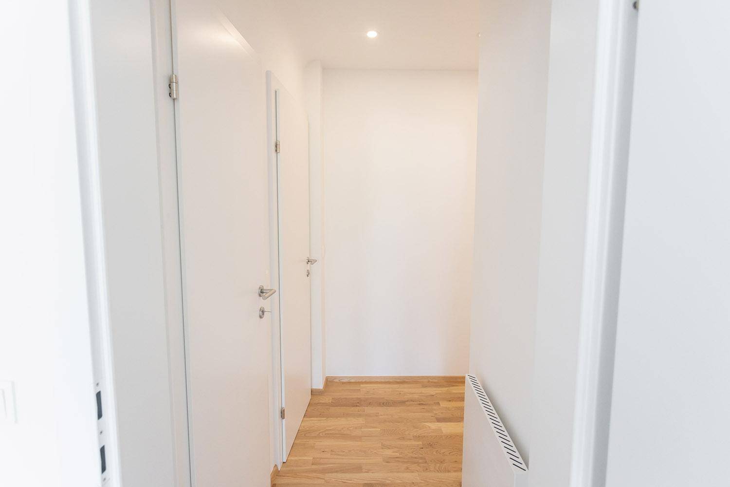 Schmaler, heller Flur mit mehreren weißen Türen, die zu den verschiedenen Zimmern der Wohnung führen.