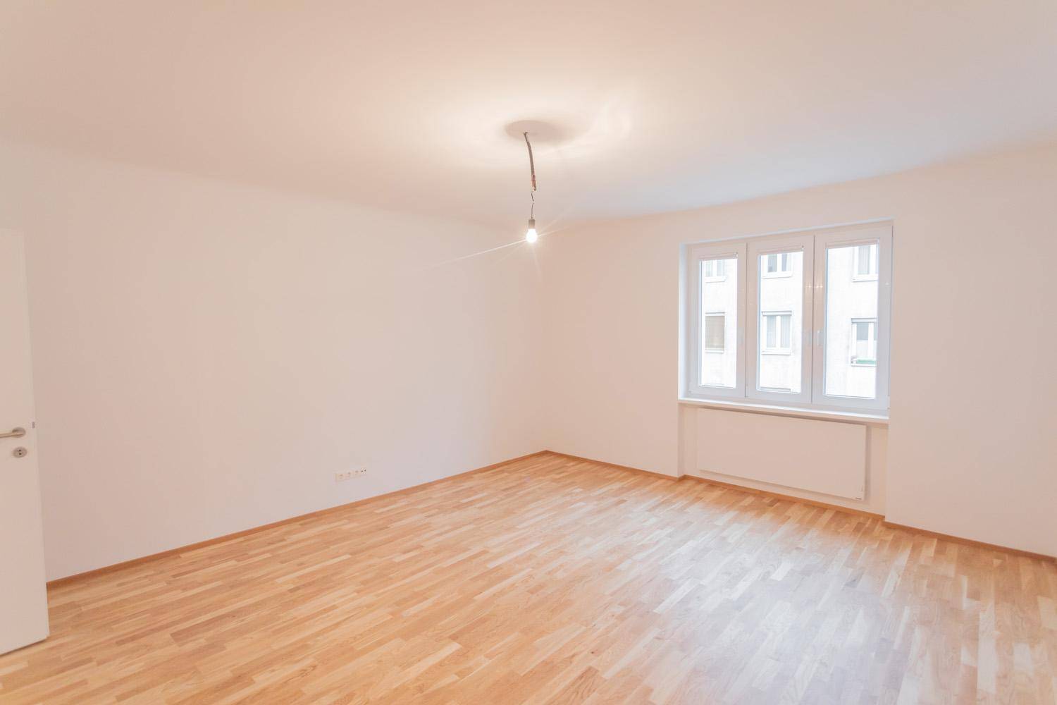 Helles und geräumiges Zimmer mit Parkettboden und großen Fenstern, bietet viel Tageslicht.