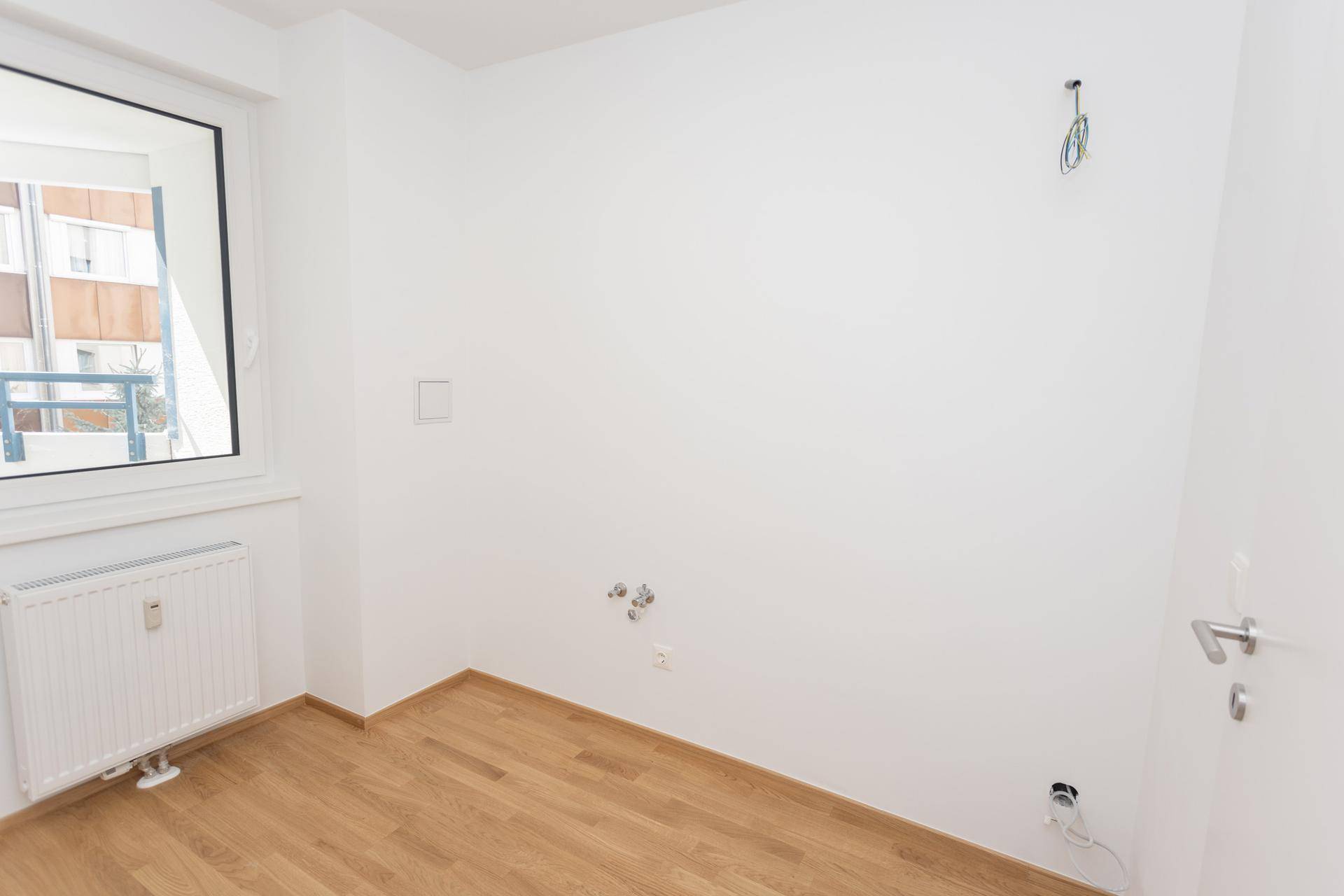 Leeres Zimmer mit hellem Parkettboden und weiß gestrichenen Wänden, vielseitig nutzbar.