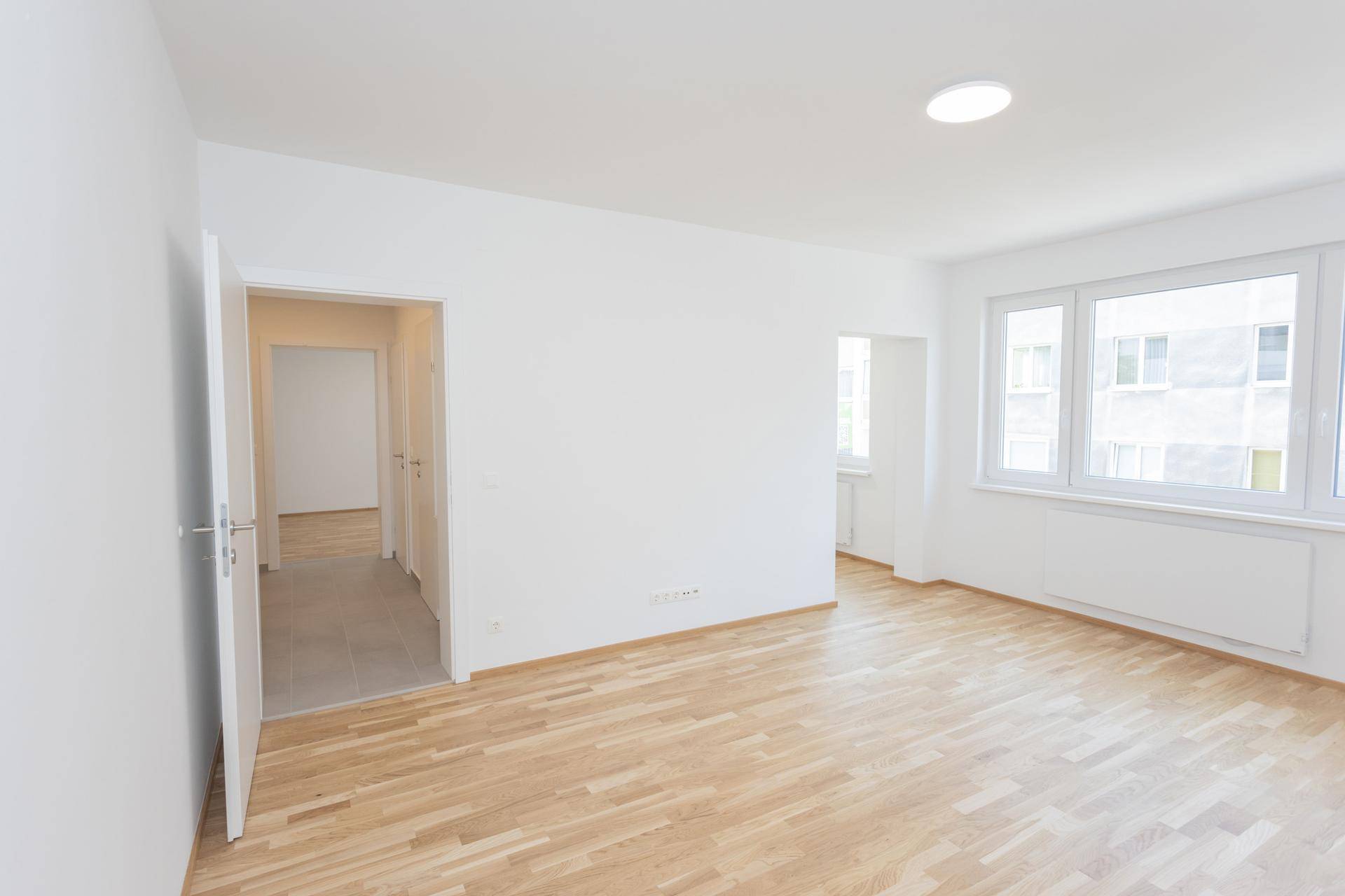 Heller Wohnbereich mit Parkettboden und Zugang zum Flur, ideal für offene Wohnkonzepte.