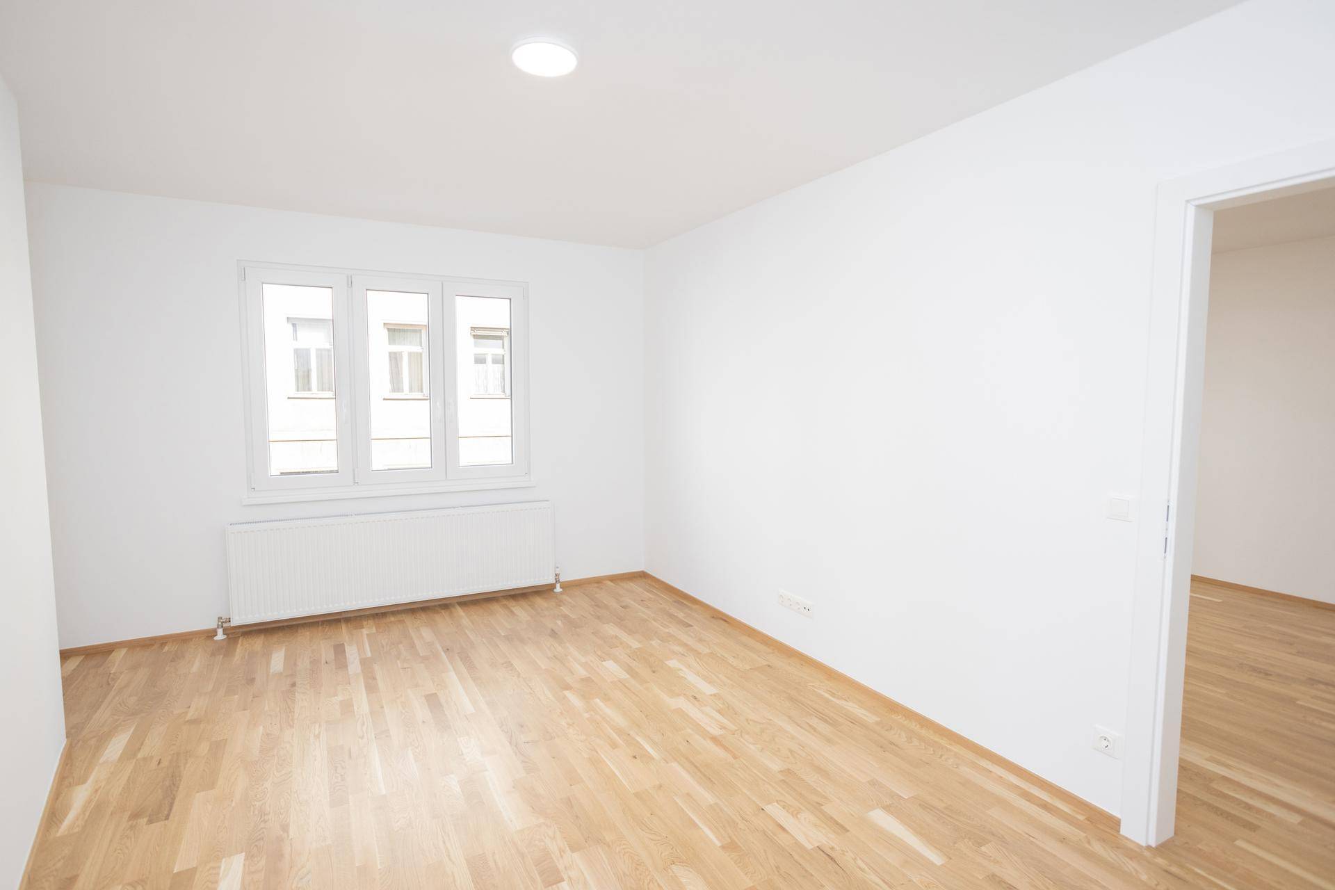 Geräumiges, unmöbliertes Zimmer mit Parkettboden und Fenster, das viel Tageslicht bietet.