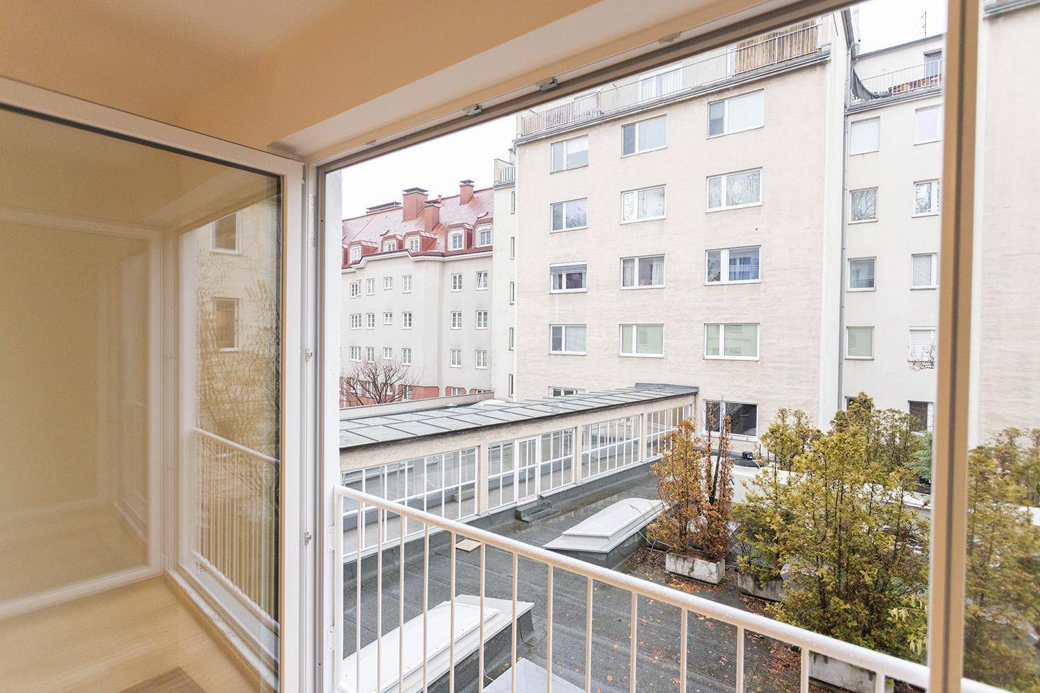 Balkon mit Blick auf die umliegenden Gebäude und einen begrünten Innenhofbereich.