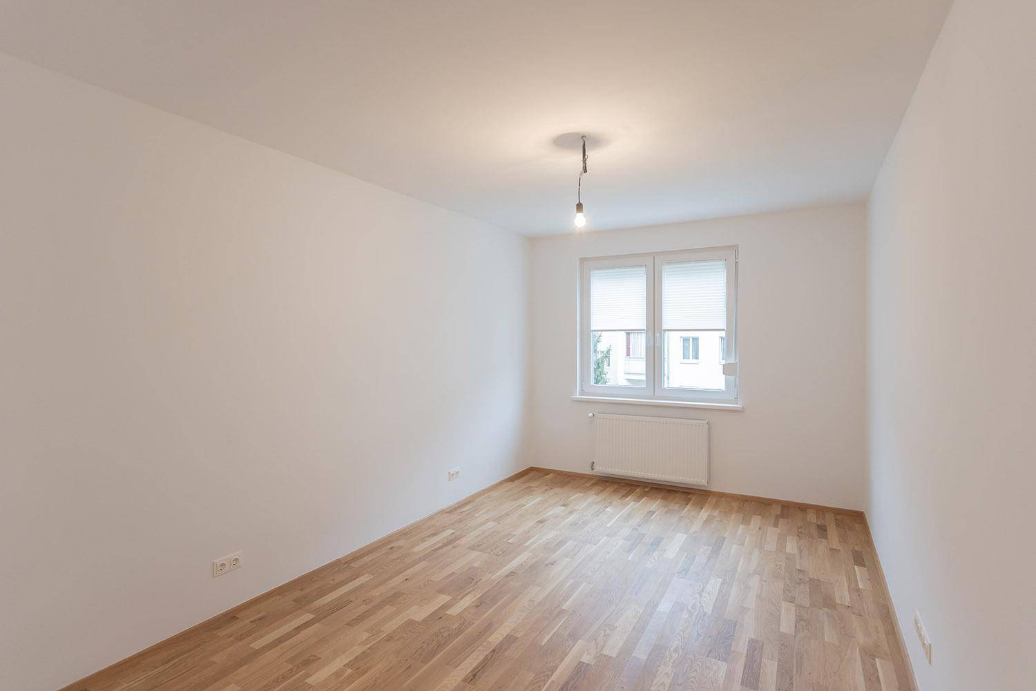 Heller Raum mit Holzboden und großem Fenster, bereit zur individuellen Gestaltung.