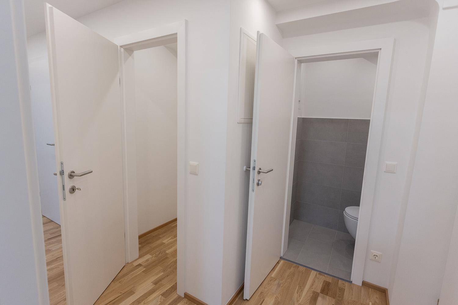 Heller Flur mit mehreren offenen Türen, darunter der Zugang zur Gästetoilette.
