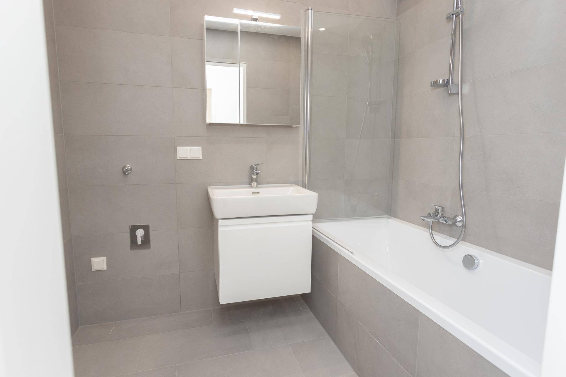 Helles Badezimmer mit Badewanne, Duschabtrennung und modernem Waschbecken, komplett saniert.