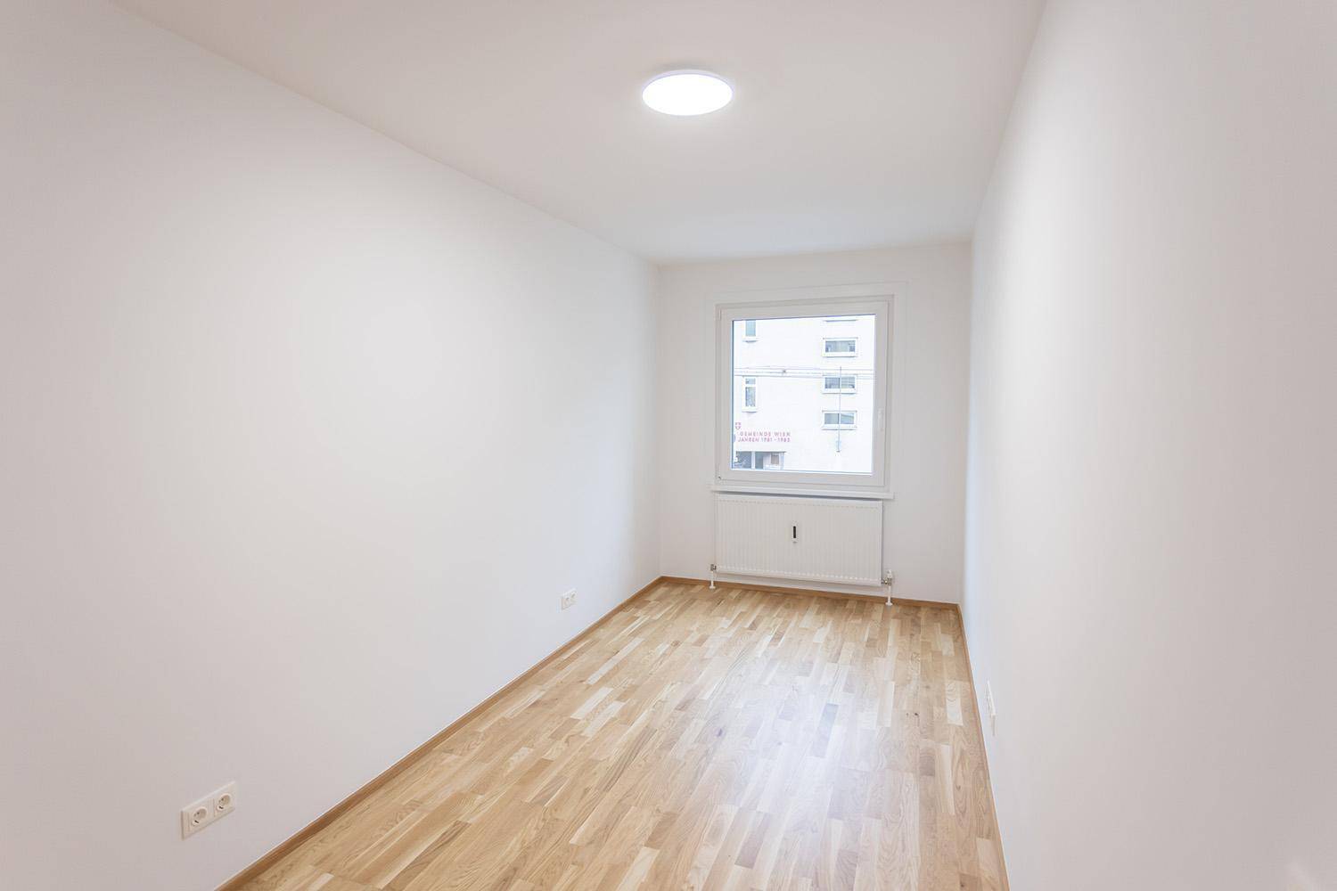 Helles, unmöbliertes Zimmer mit Parkettboden und einem Fenster, ideal als Schlaf- oder Arbeitszimmer.