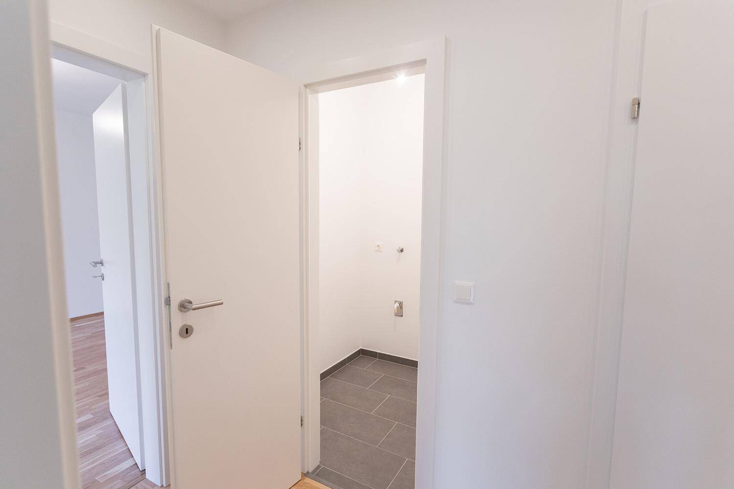 Kleiner Hauswirtschaftsraum mit Fliesenboden und Anschlüssen für Waschmaschine.