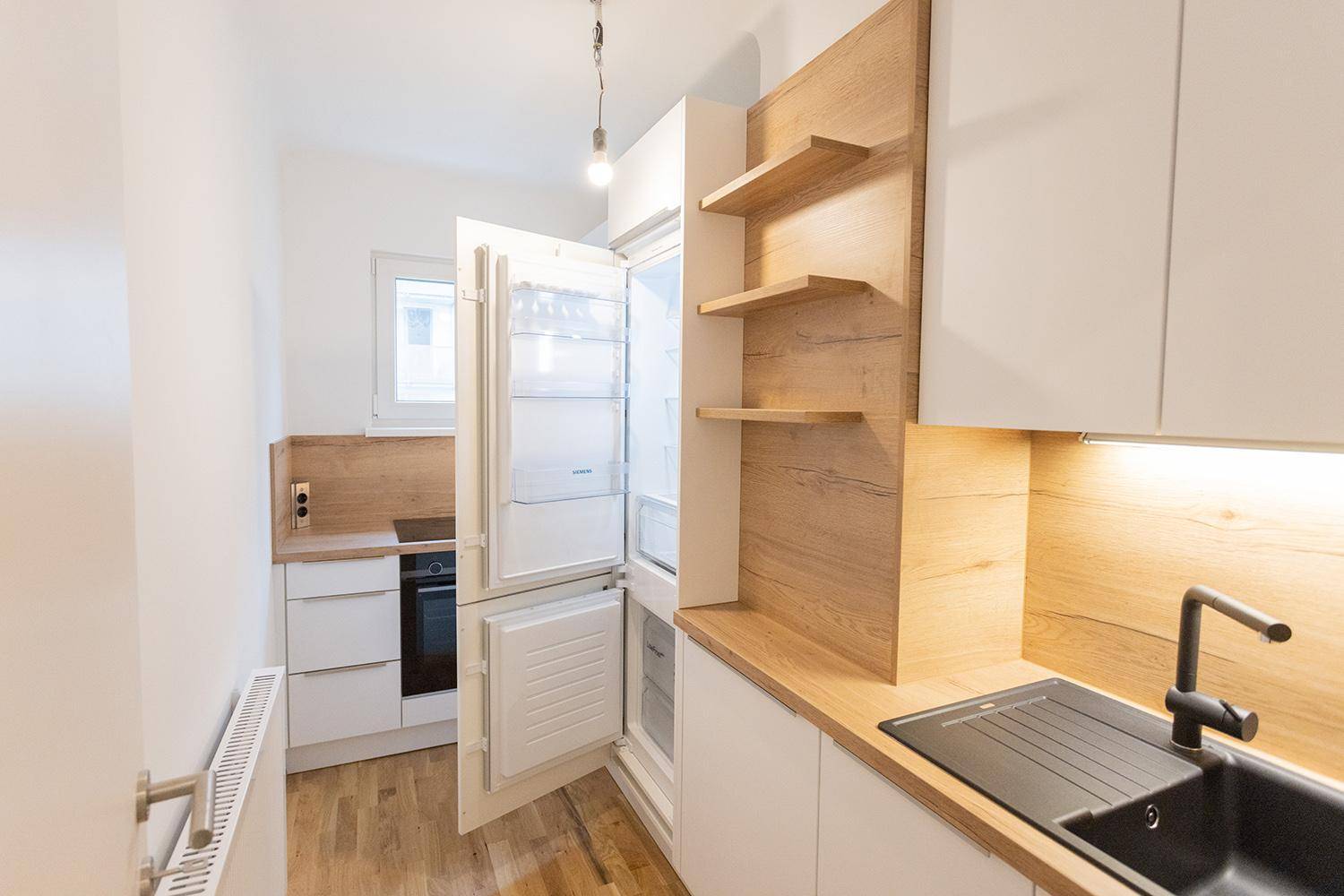Küchenzeile mit integriertem Kühlschrank, Induktionskochfeld, Backofen und Spüle.