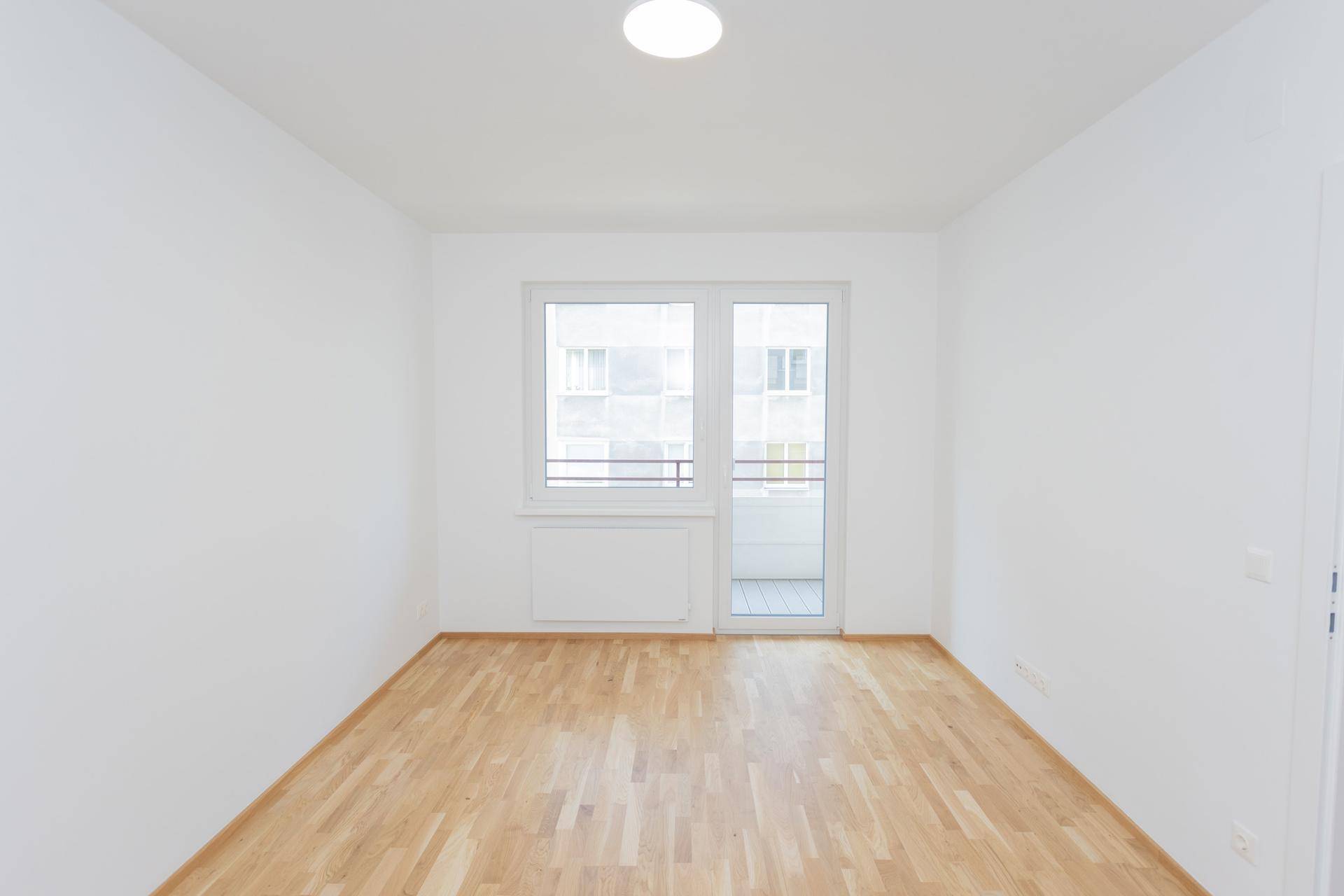 Geräumiges Schlafzimmer mit Parkettboden und Balkontür, ideal für eine ruhige Wohnatmosphäre.