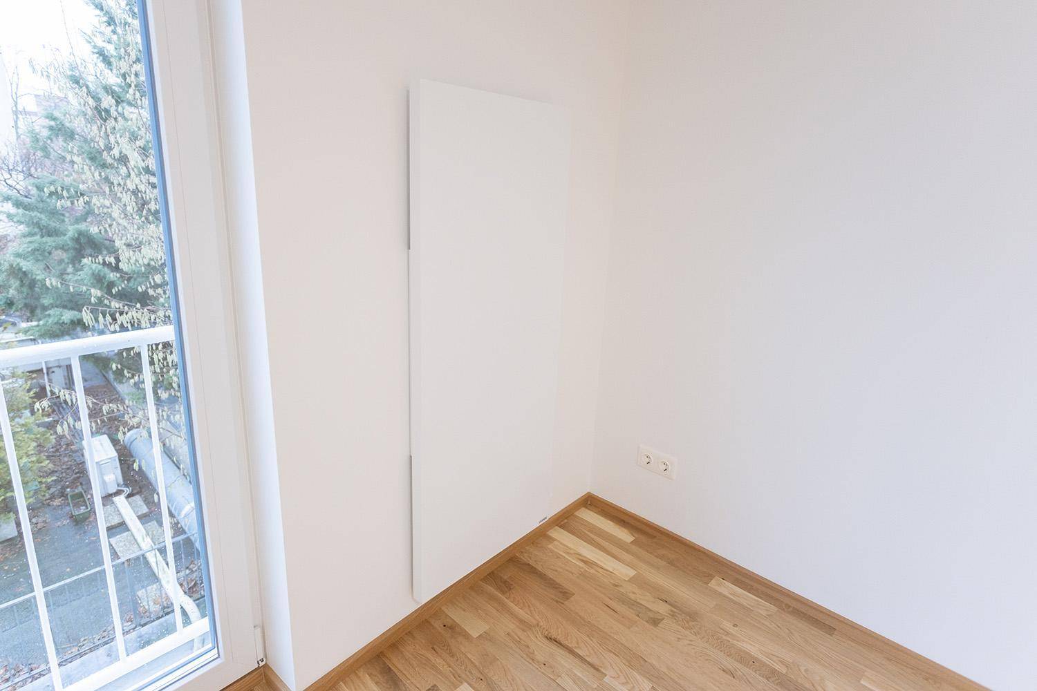 Ecke eines hellen Zimmers mit Heizkörper und Zugang zu einem Außenbereich.