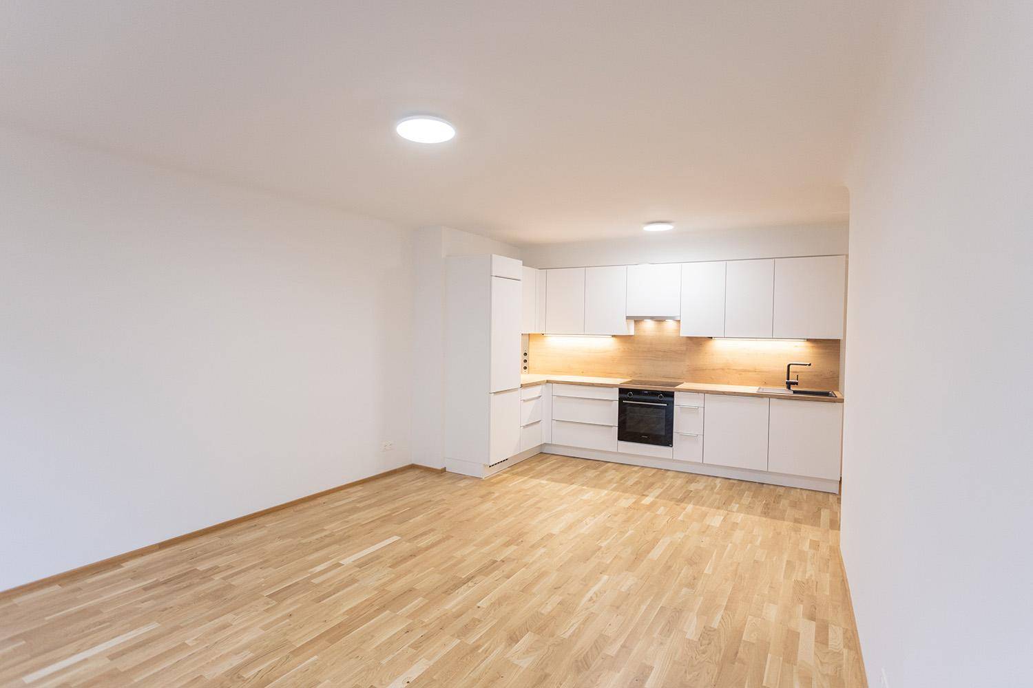 Moderne Einbauküche mit weißen Schränken, Holz-Arbeitsplatte und integrierten Geräten.