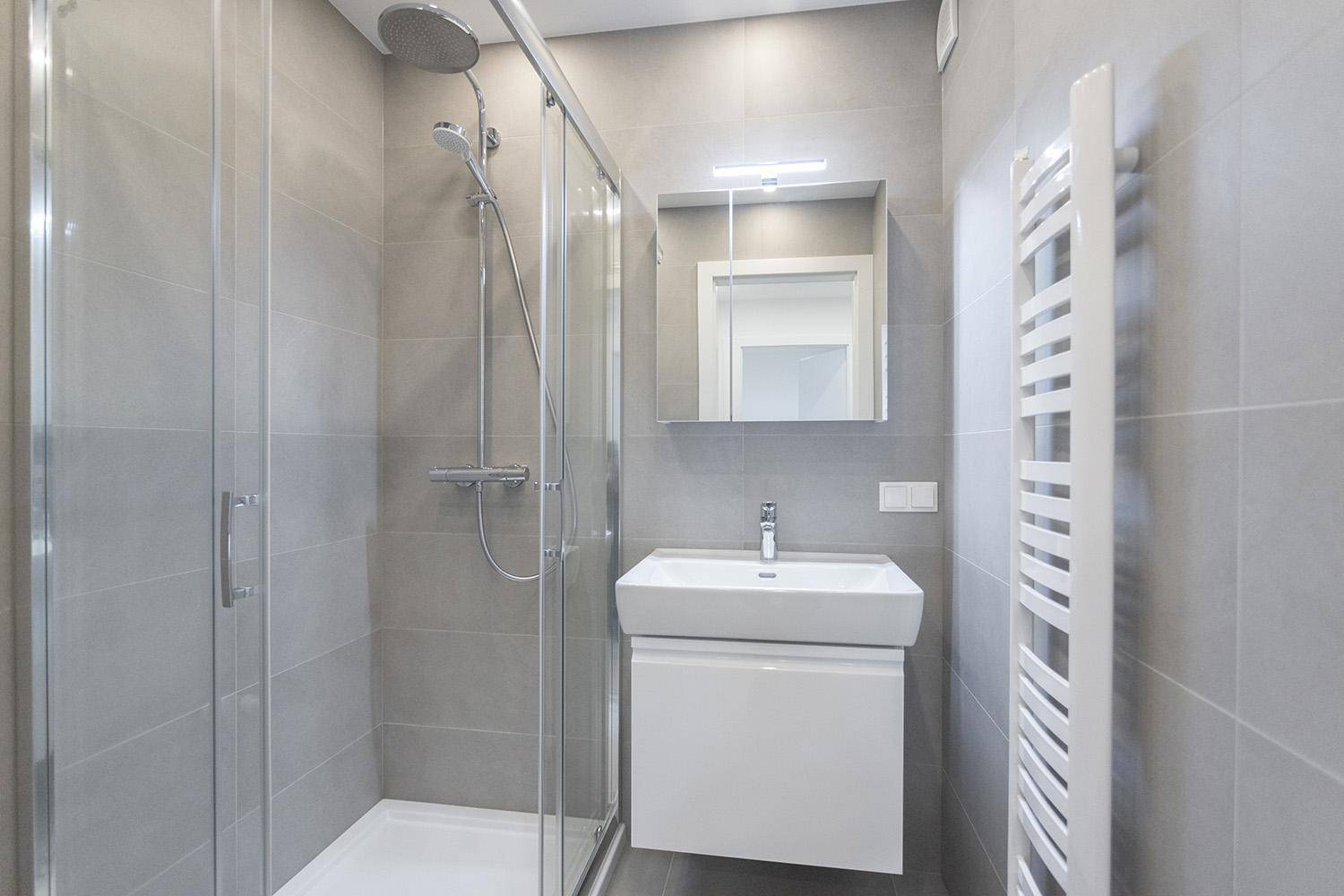 Modernes Badezimmer mit Duschkabine, Waschbecken und beheiztem Handtuchhalter.