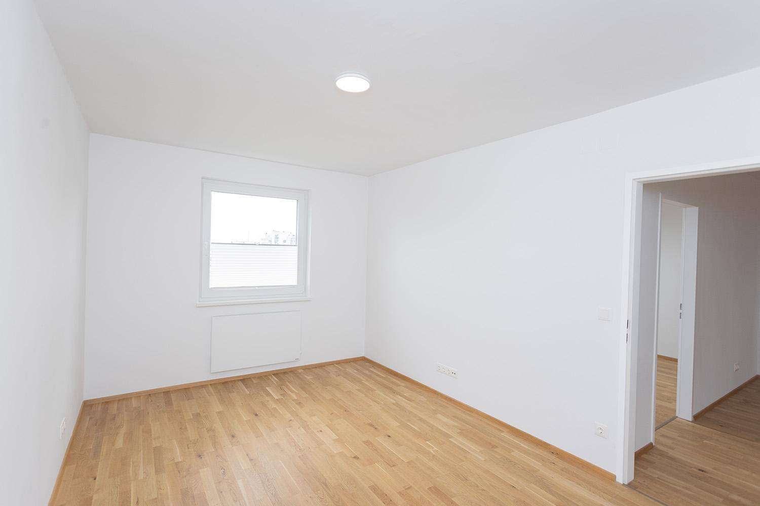 Helles Zimmer mit Eichenparkett und Fenster, ideal als Schlaf- oder Arbeitszimmer.
