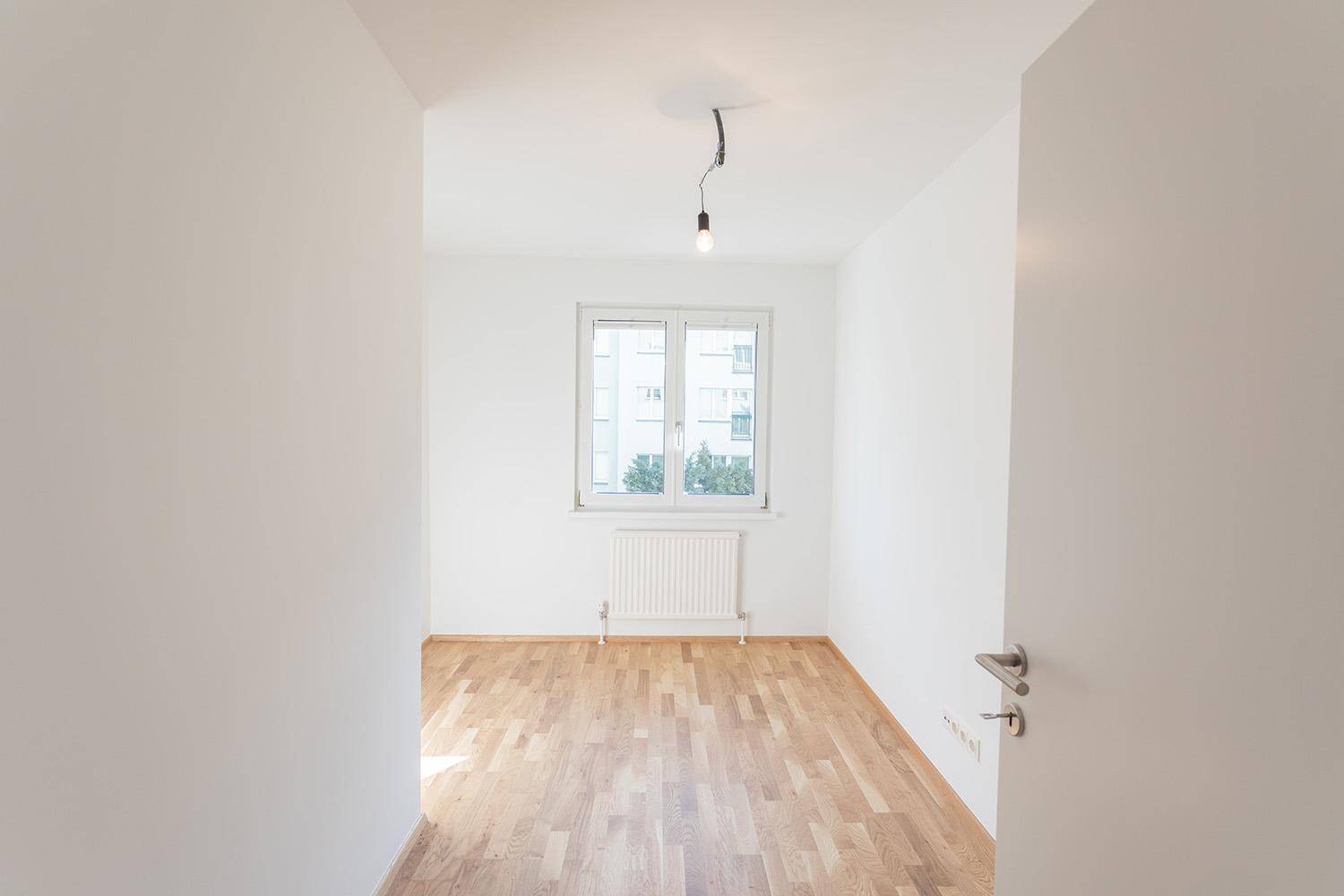 Heller Raum mit Parkettboden und Fenster, das viel natürliches Licht spendet.