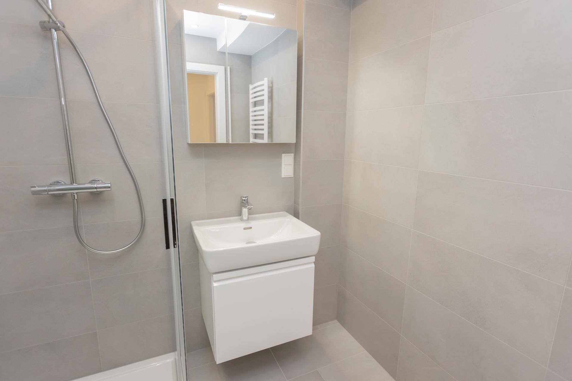 Modernes Badezimmer mit Duschkabine, Waschbecken und Spiegel mit Beleuchtung.