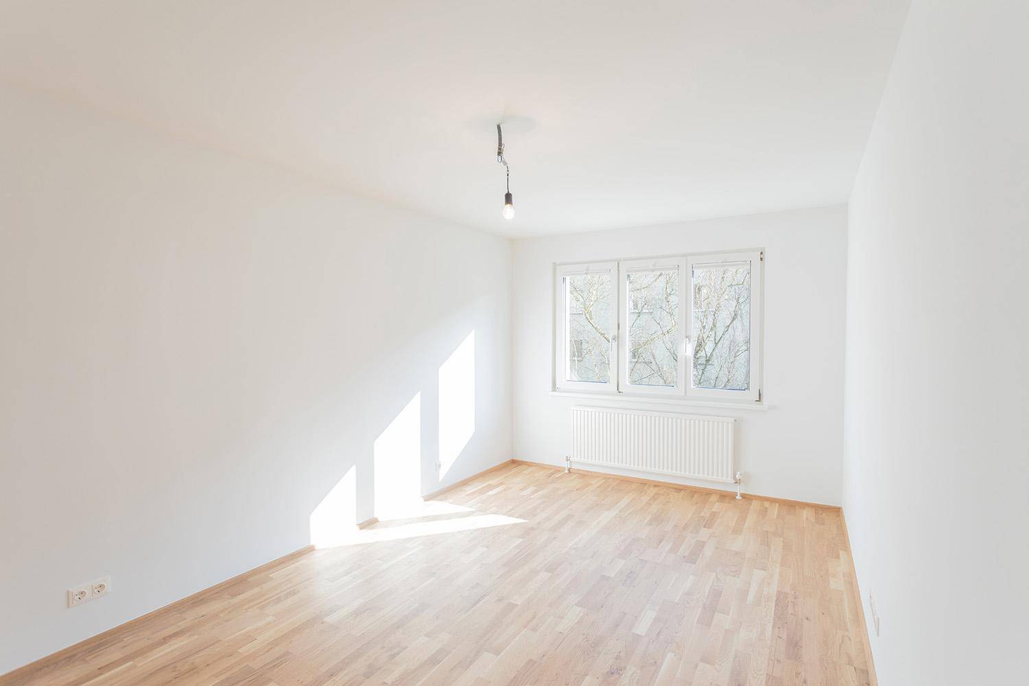 Geräumiger, heller Raum mit Parkettboden und großem Fenster, das viel Licht bietet.