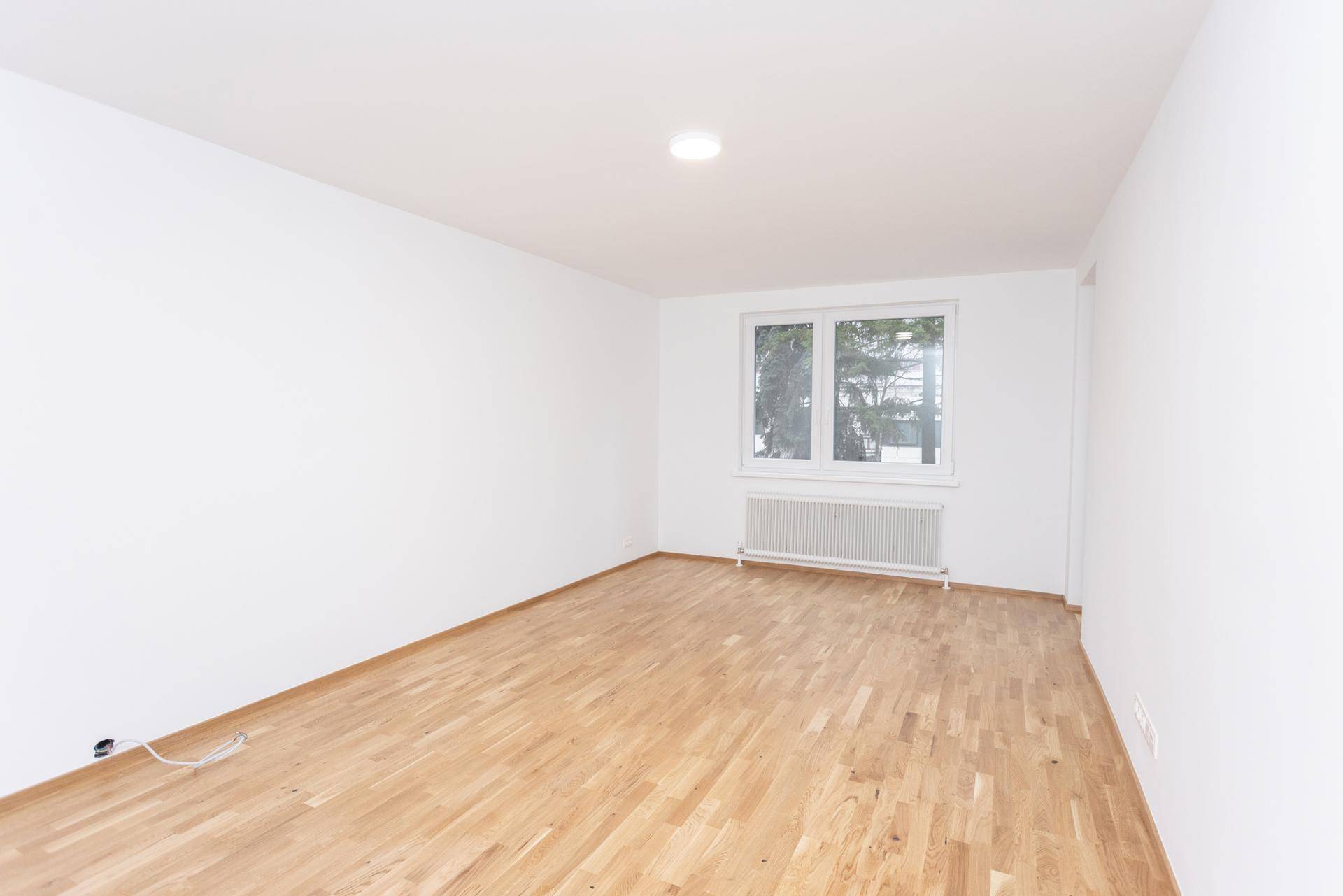Großer, heller Raum mit Parkettboden und Fenster, vielseitig nutzbar.