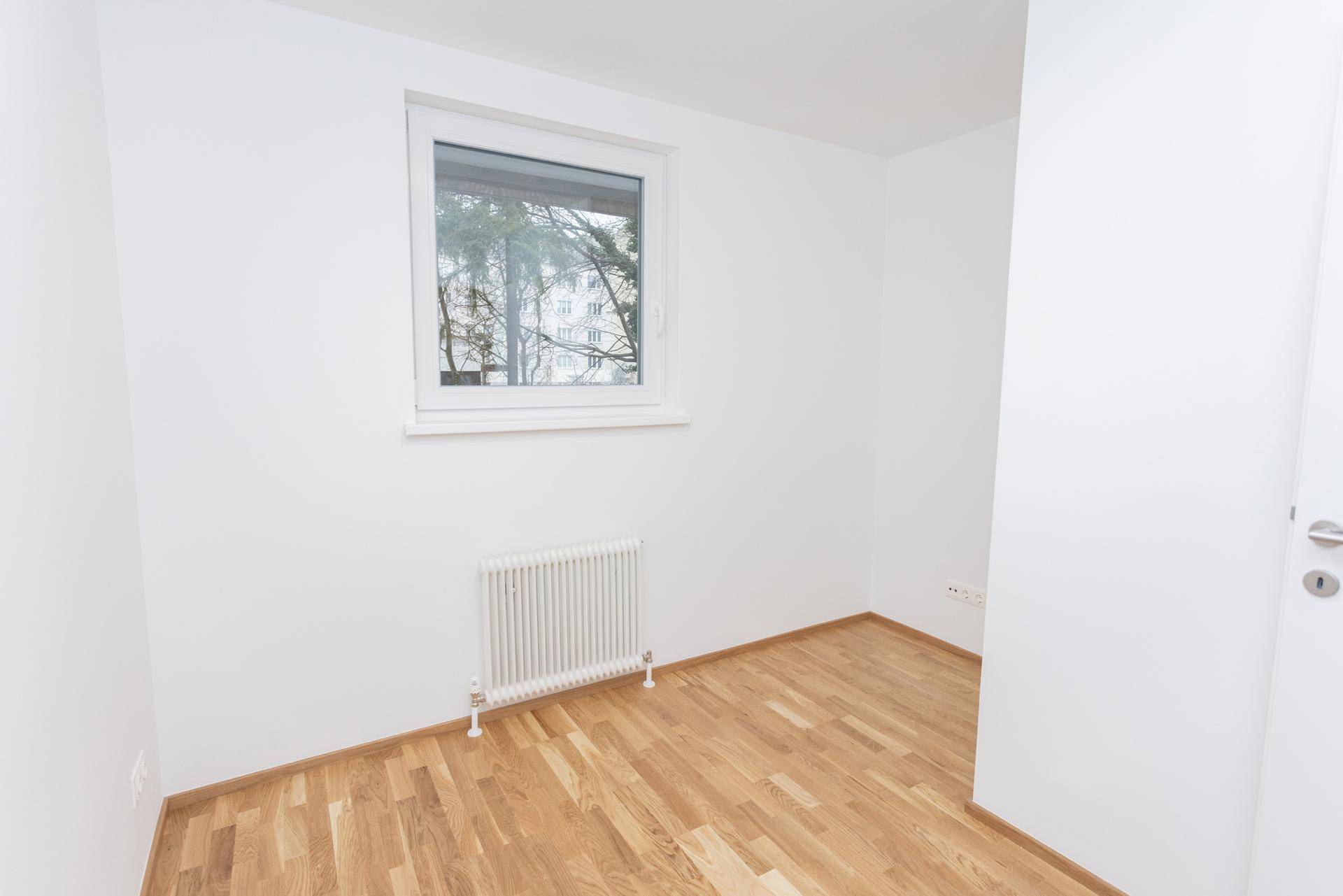 Heller, leerer Raum mit Parkettboden und Fenster, bereit zur individuellen Gestaltung.