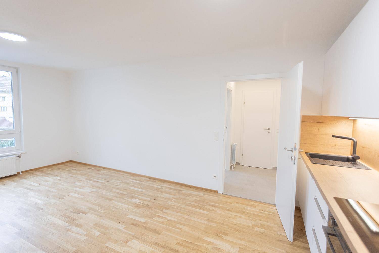 Heller Wohnbereich mit Holzboden und Blick auf die moderne Küche.