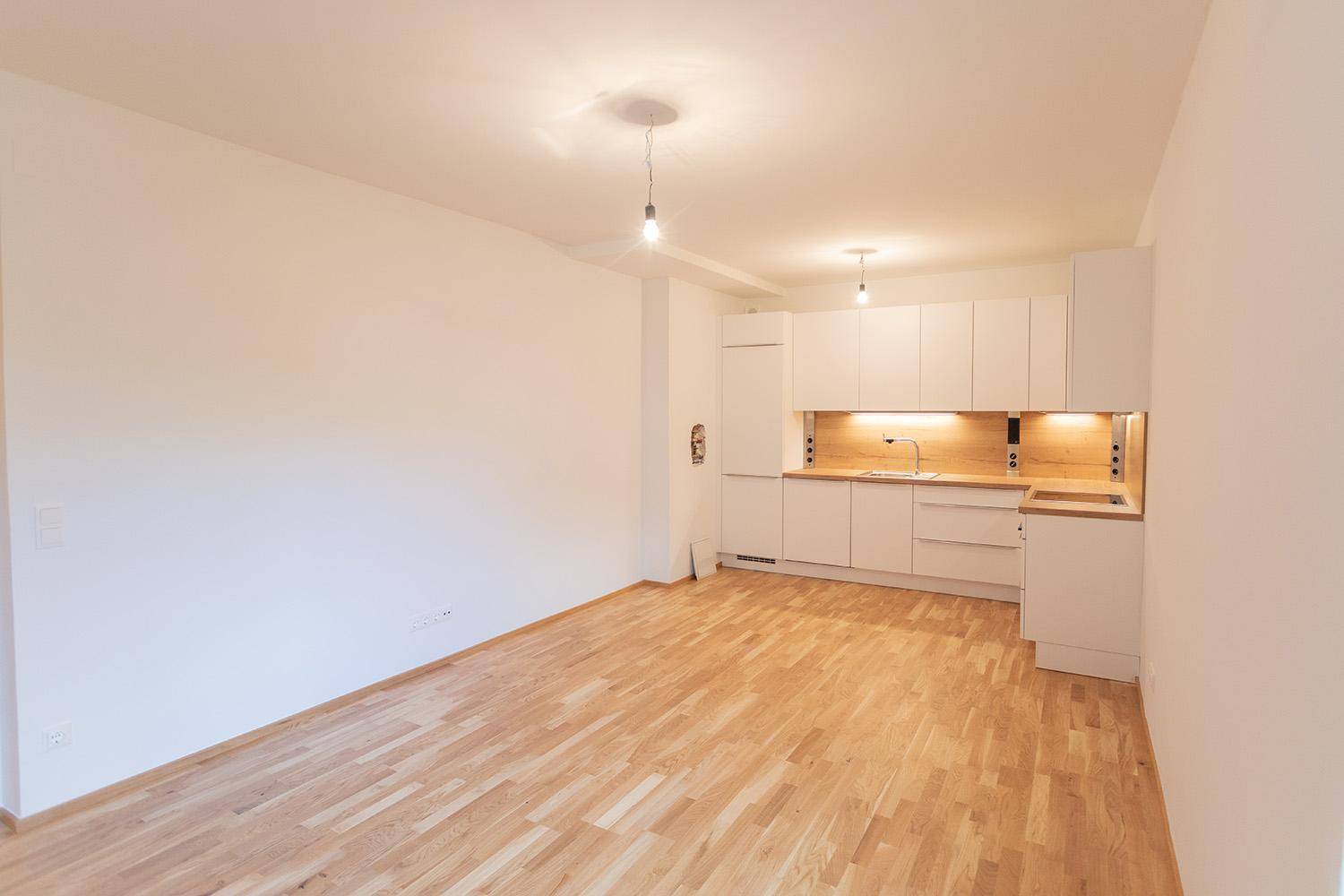 Offener Wohnbereich mit integrierter moderner Einbauküche und Holzboden.