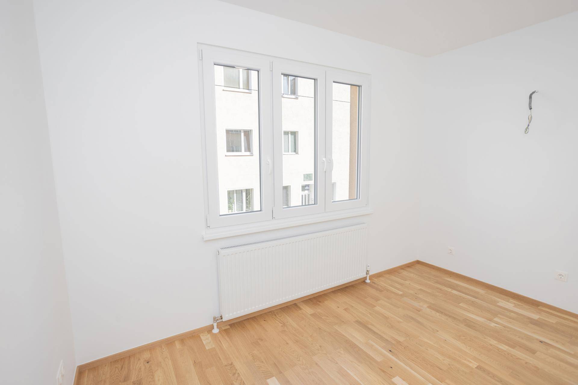 Helles, unmöbliertes Zimmer mit Parkettboden und großem Fenster, ideal als Schlaf- oder Arbeitszimmer.