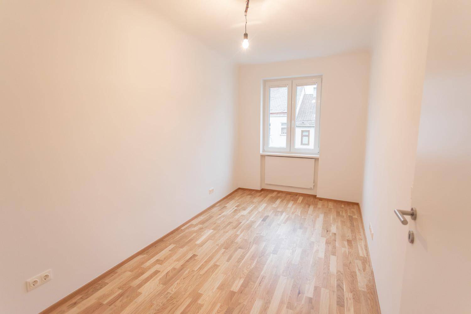 Helles Zimmer mit Parkettboden und Fenster, ideal als Schlaf- oder Arbeitszimmer.