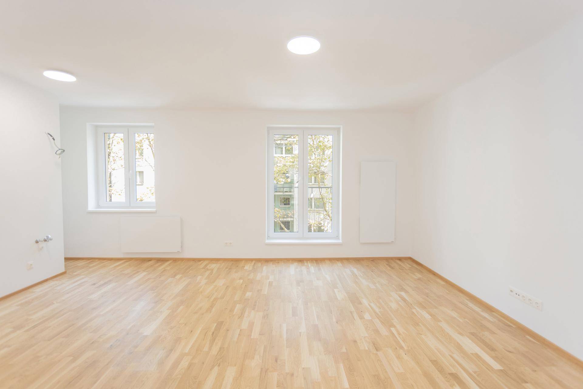 Helles und geräumiges Wohnzimmer mit Parkettboden und Blick ins Grüne.