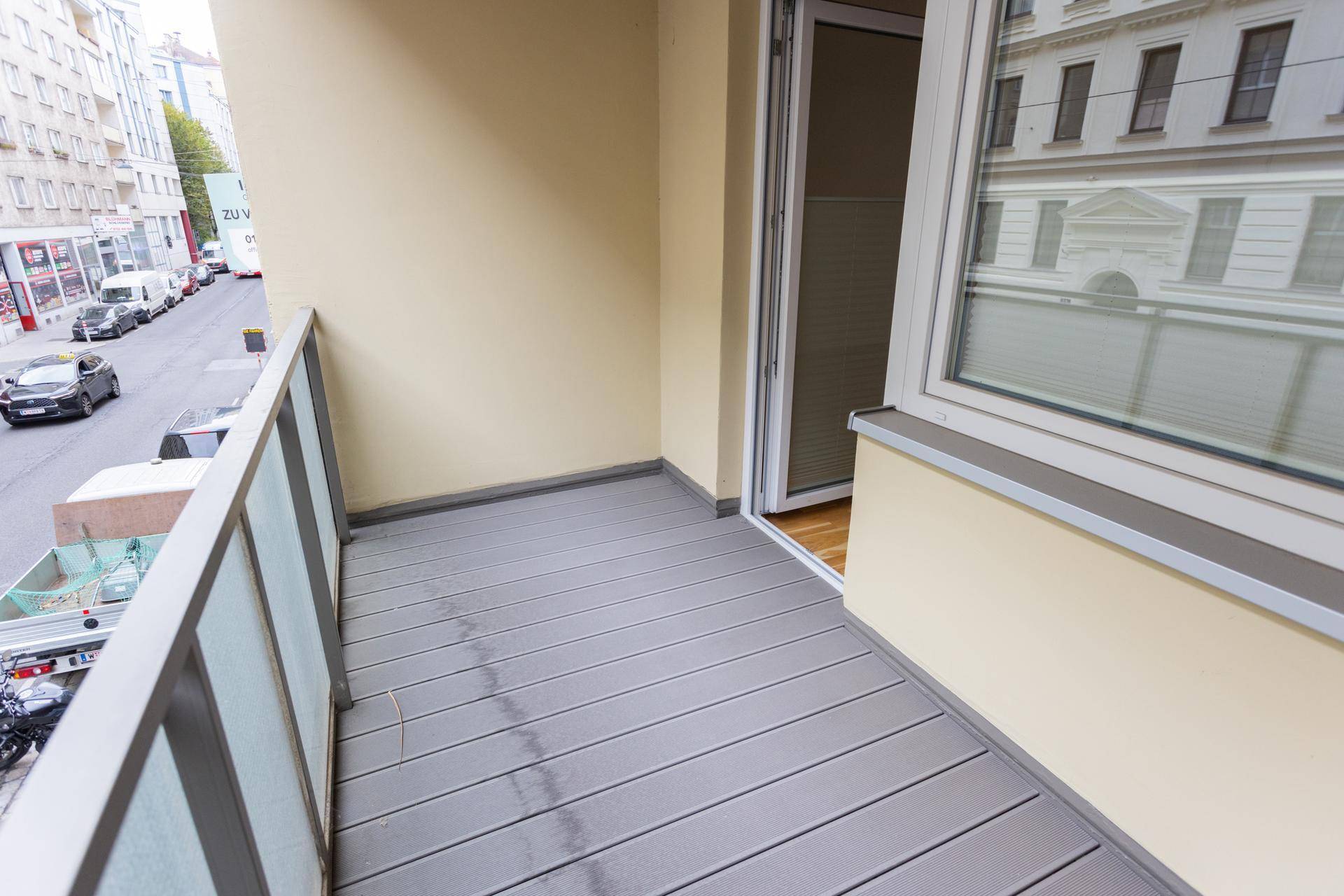 Geräumiger Balkon mit modernem Dielenboden und Blick auf die belebte Stadtstraße.