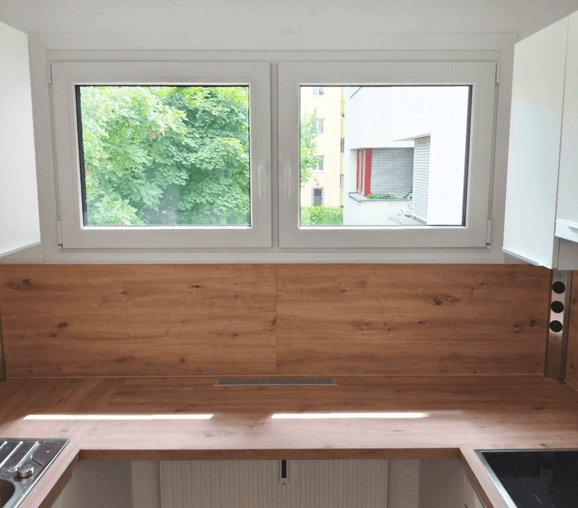 Moderne Küche mit Holzoptik-Arbeitsplatte, Spüle und Blick ins Grüne.