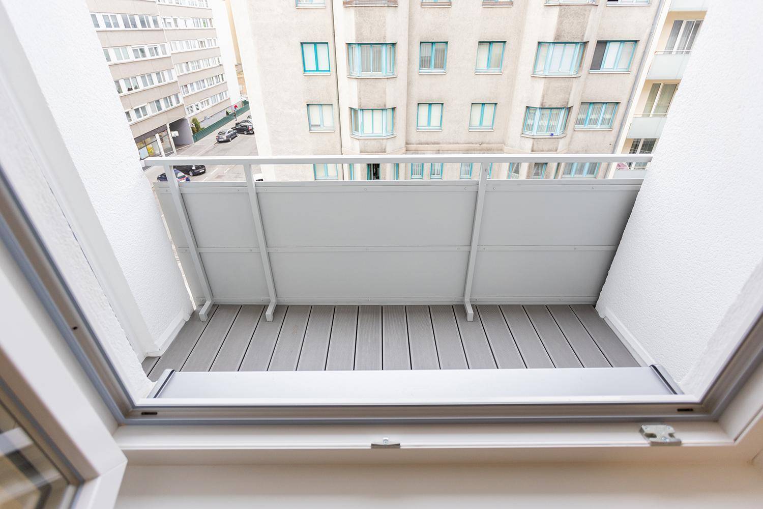 Kleiner Balkon mit grauem Bodenbelag und Blick auf die umliegenden Stadtgebäude.