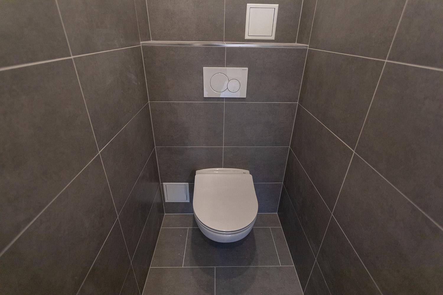 Modernes Gäste-WC mit dunkelgrauen Fliesen an Wänden und Boden sowie wandhängendem WC.