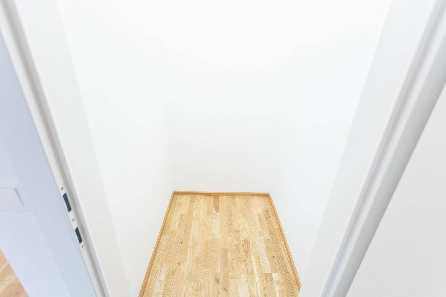 Leerer Raum mit Holzboden und weißen Wänden, bereit zur individuellen Gestaltung.