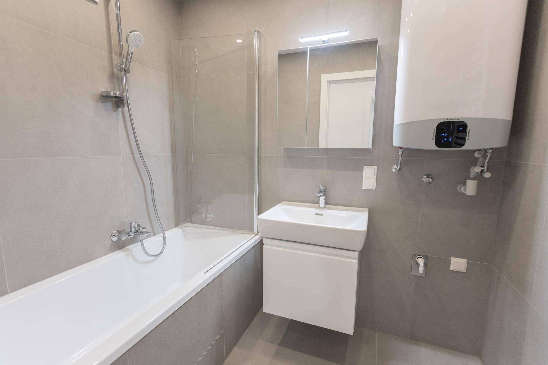 Modernes Badezimmer mit Badewanne, integrierter Dusche und Waschbecken in hellen Grautönen.