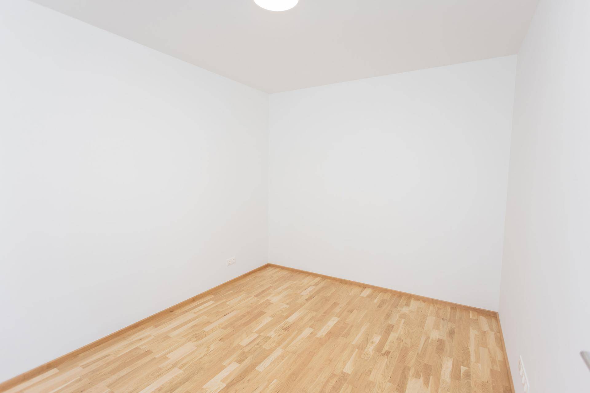 Leerer Raum mit hellen Wänden und einem warmen Holzfußboden, bereit zur individuellen Gestaltung.