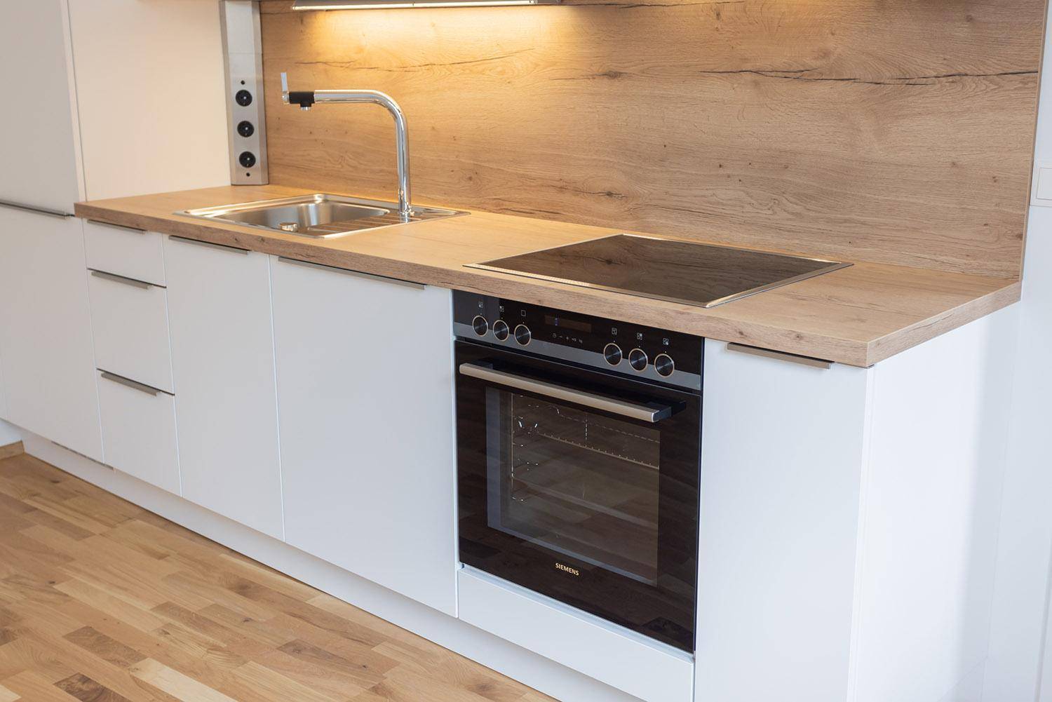 Detailansicht der modernen Einbauküche mit Siemens Backofen, Induktionskochfeld und Spüle.