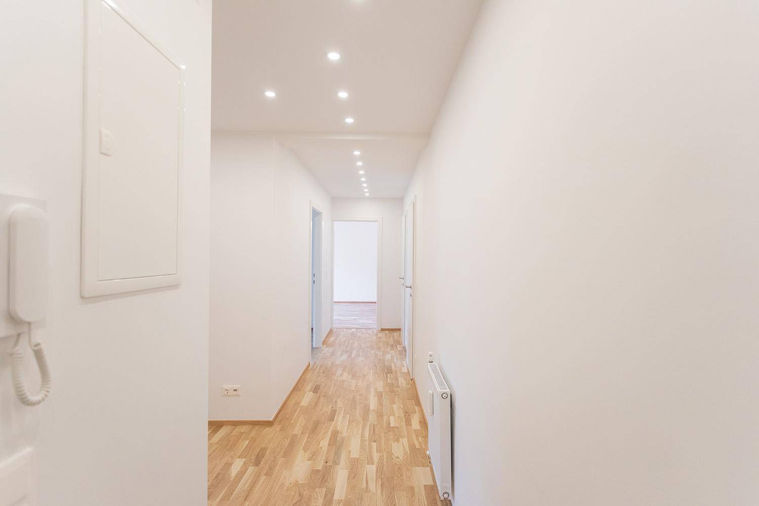 Langer, heller Flur mit Holzboden und Deckenstrahlern, der die verschiedenen Bereiche der Wohnung verbindet.