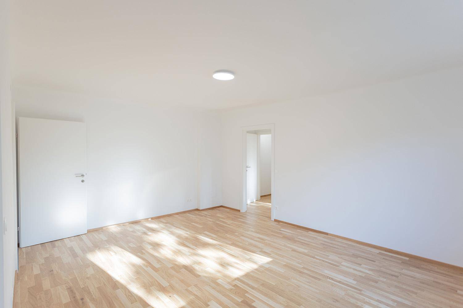 Heller, leerer Raum mit Holzboden und viel Tageslicht, bereit zur individuellen Gestaltung.