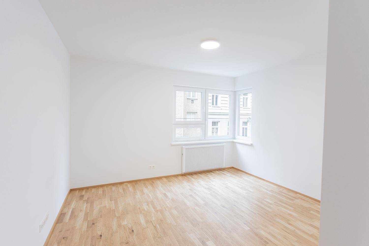 Helles Schlafzimmer mit Holzparkettboden und großen Fenstern, bereit zur Einrichtung.