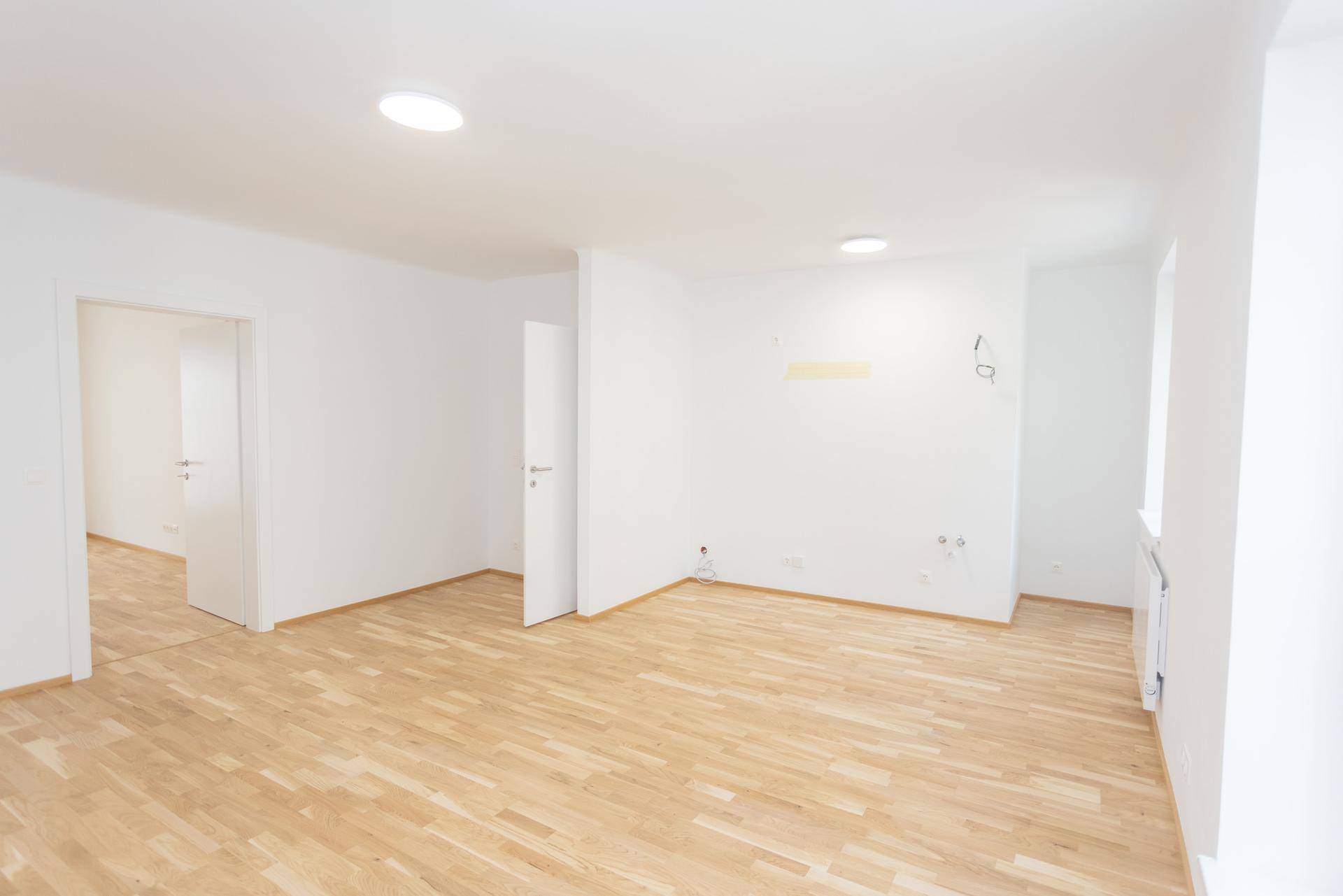 Großes Wohnzimmer mit Parkettboden und Zugang zu weiteren Räumen der Wohnung.