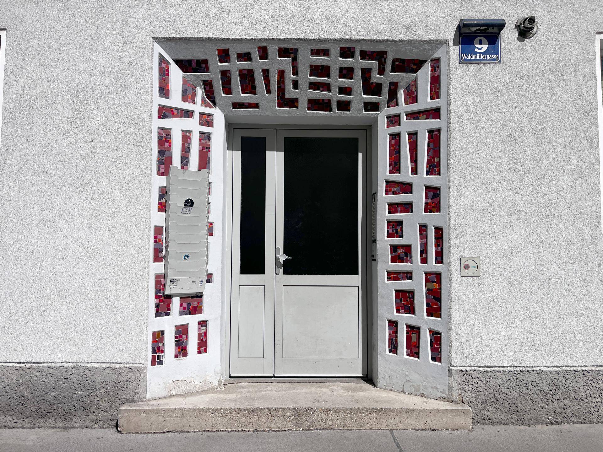 Eingangsbereich eines Wohnhauses mit dekorativer Fassadengestaltung und Haustür.