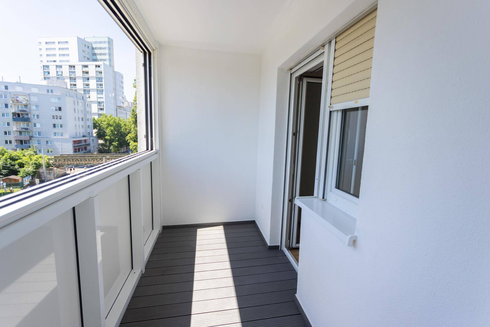 Heller Balkon mit modernem Bodenbelag und weitem Ausblick auf die Stadtbebauung und Grünflächen.