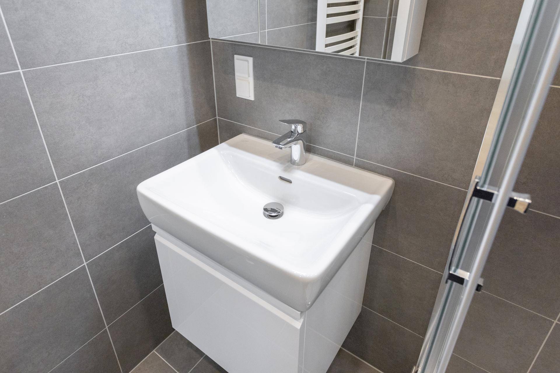 Modernes Waschbecken mit Unterschrank und Armatur im gefliesten Badezimmer.