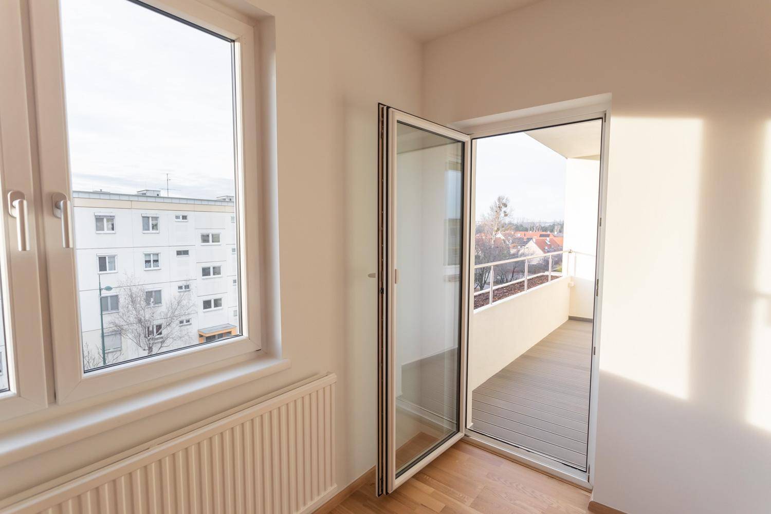 Helles Zimmer mit Parkettboden und direktem Zugang zu einem sonnigen Balkon.
