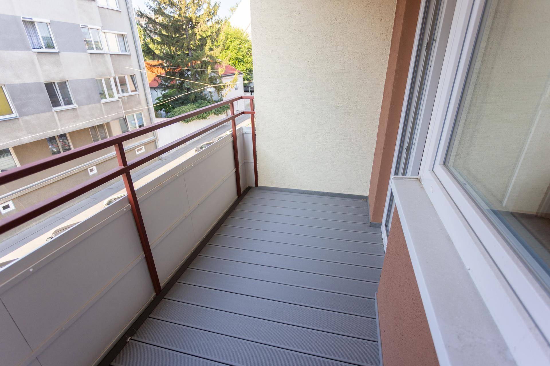 Heller Balkon mit robustem Bodenbelag und Metallgeländer, bietet Platz im Freien.