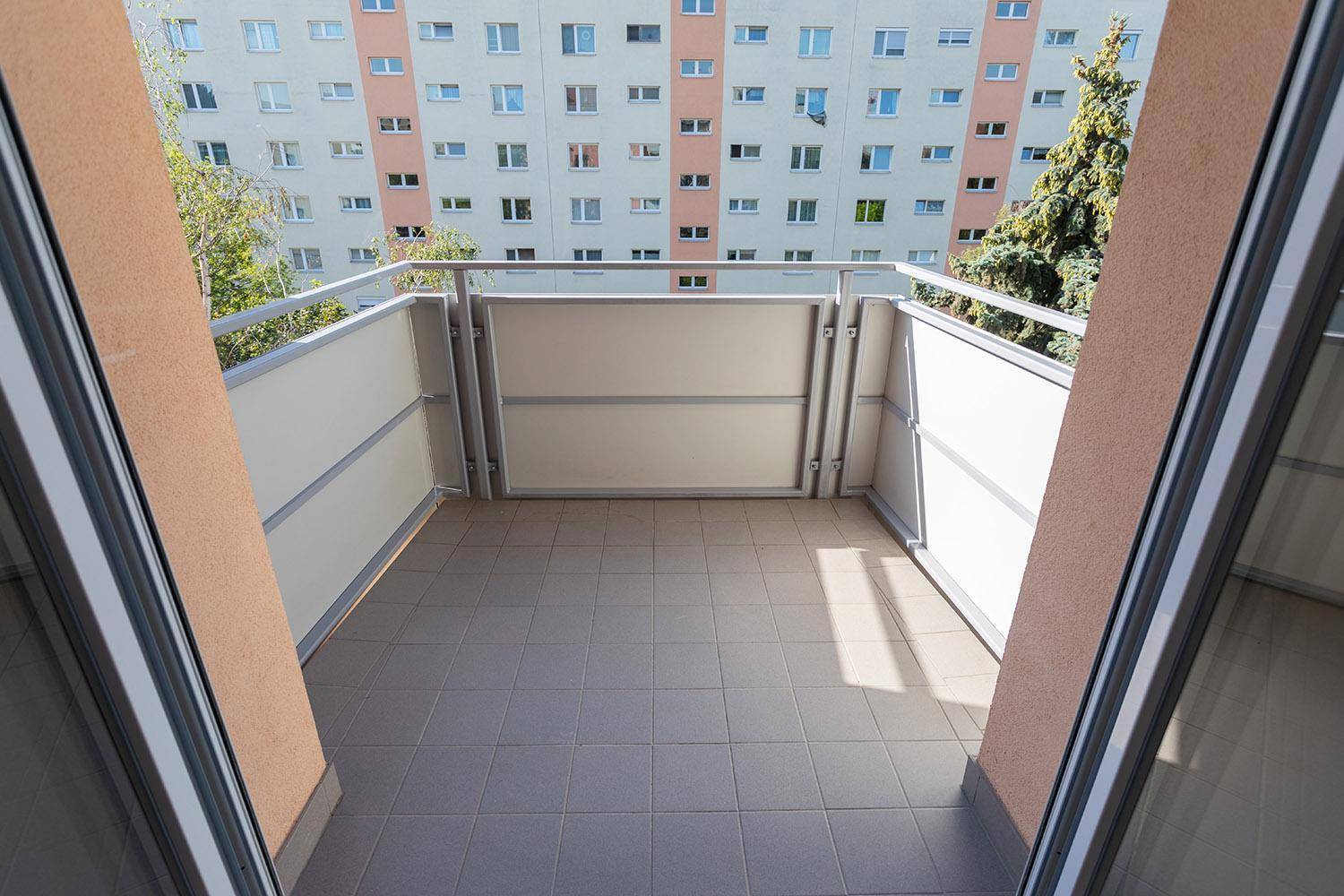 Heller Balkon mit Fliesenboden und Blick auf die umliegenden Gebäude.