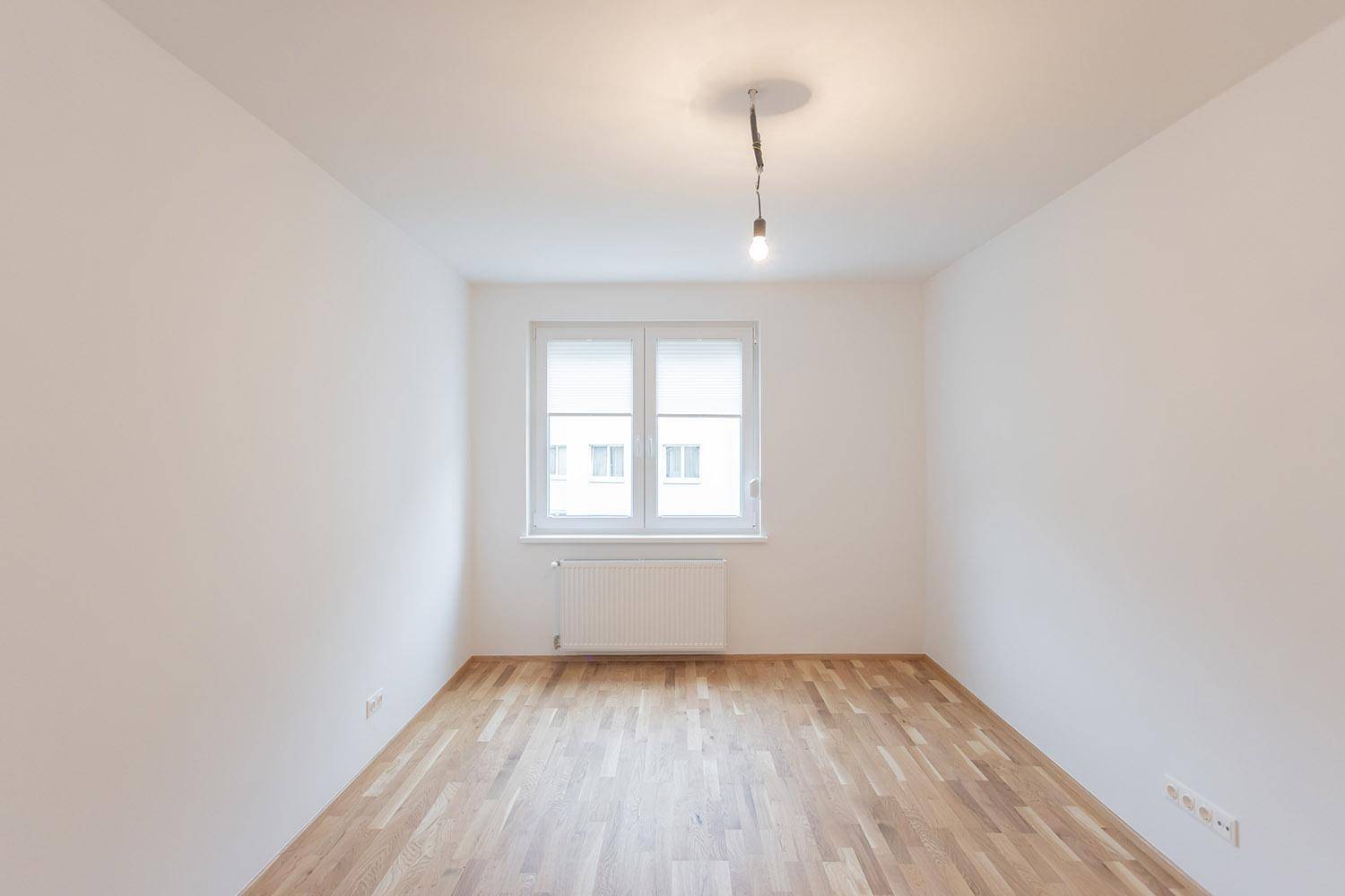 Leerer Raum mit Holzboden und Fenster, ideal für Schlafzimmer oder Arbeitszimmer.