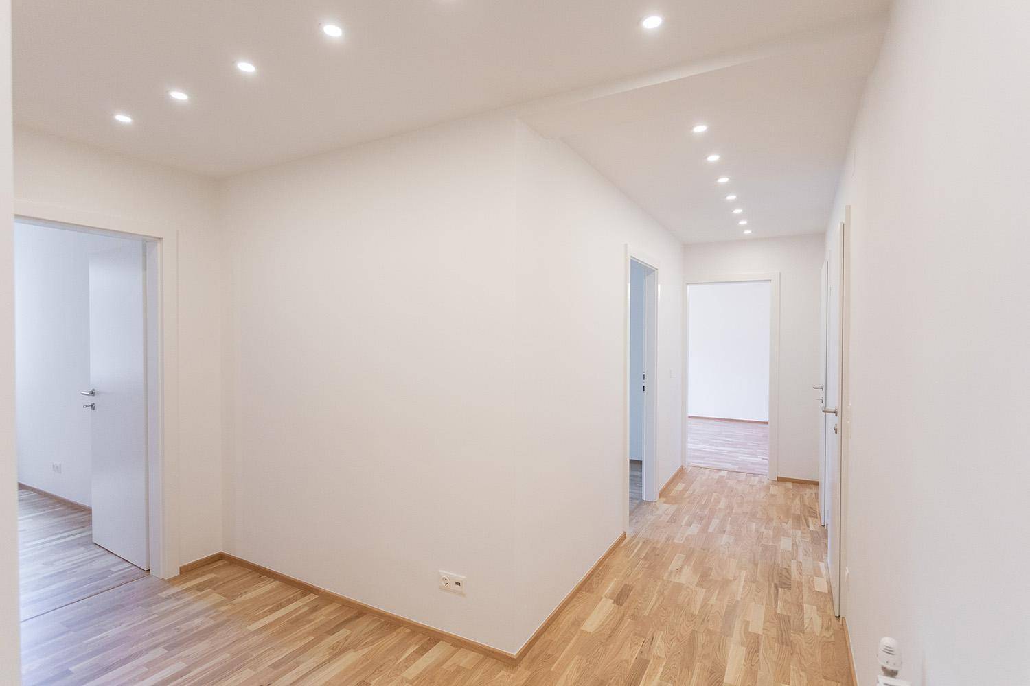 Geräumiger Flur mit Holzboden und Zugang zu verschiedenen Zimmern der Wohnung.