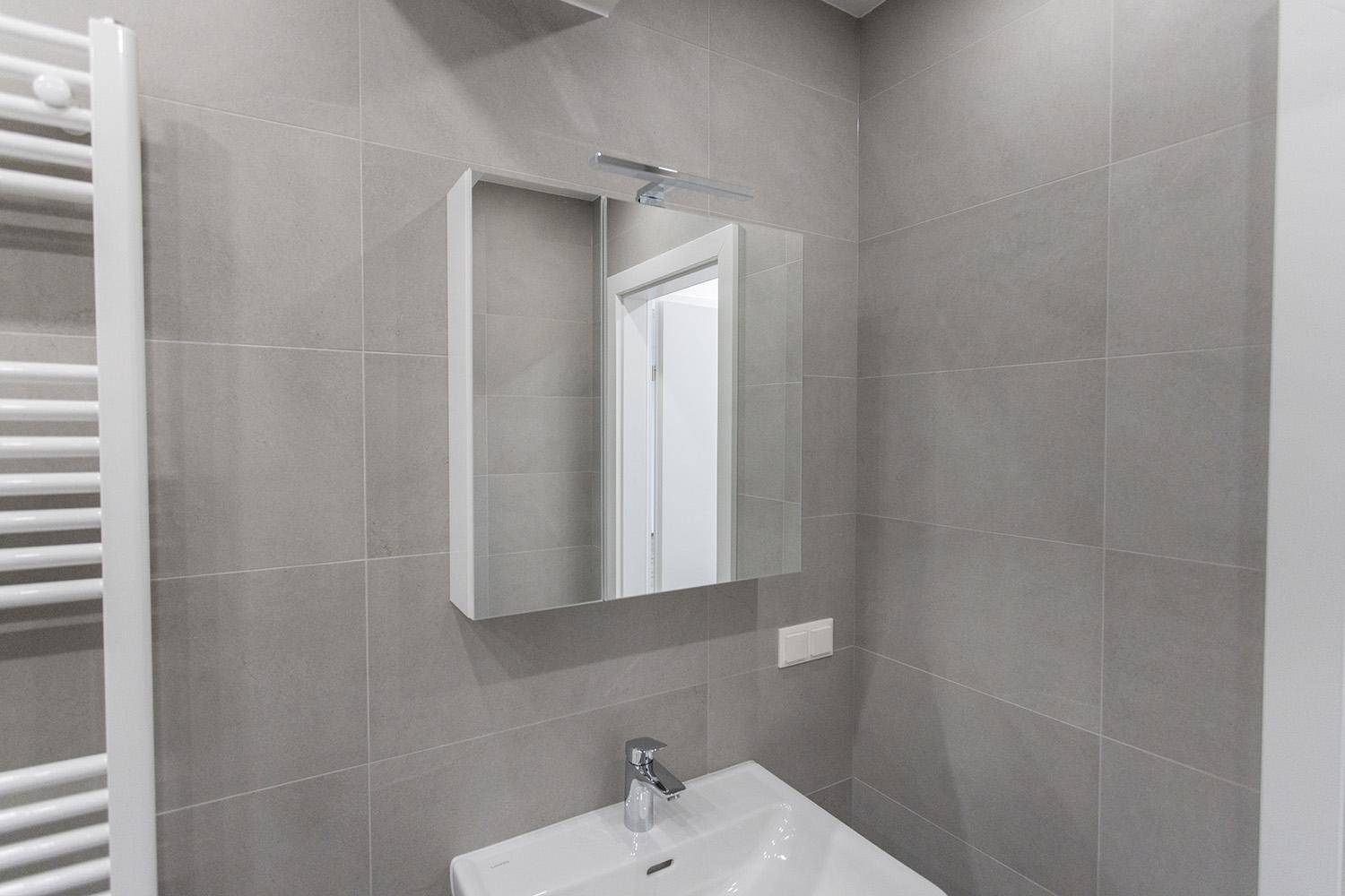 Detailansicht des Waschbeckens mit Spiegelschrank und moderner Armatur im Badezimmer.