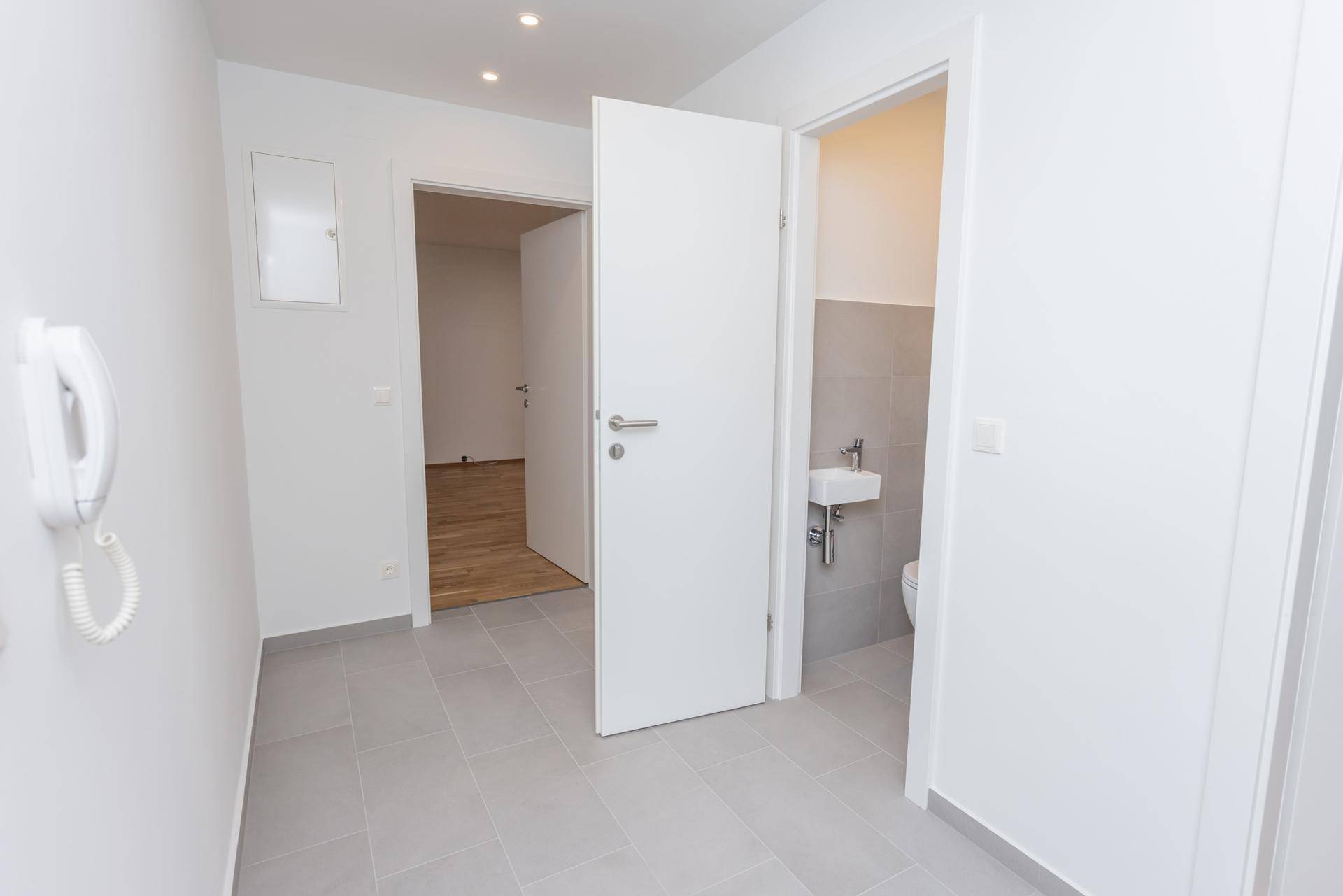 Heller Flur mit Zugang zu einem Gäste-WC und weiteren Zimmern.